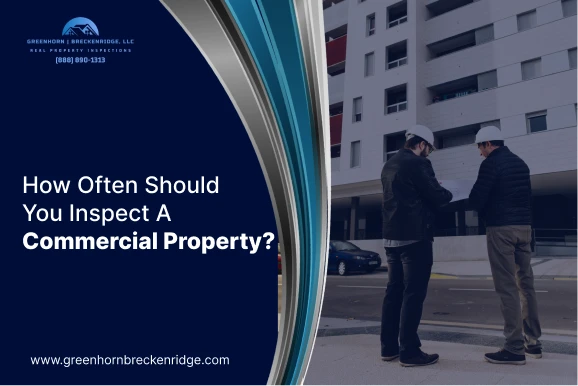 Two inspectors in hard hats reviewing documents outside a large commercial building for a property inspection.